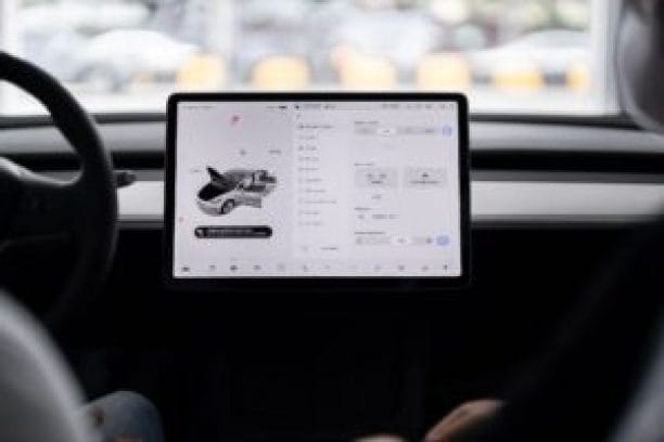 A close-up view of a car's interior showing a large touchscreen display with various interface elements, including vehicle controls and a digital graphic of an airplane.