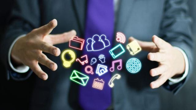 A person in a suit holds hands out, surrounded by colorful digital icons representing various app features, like messaging, social media, and music.