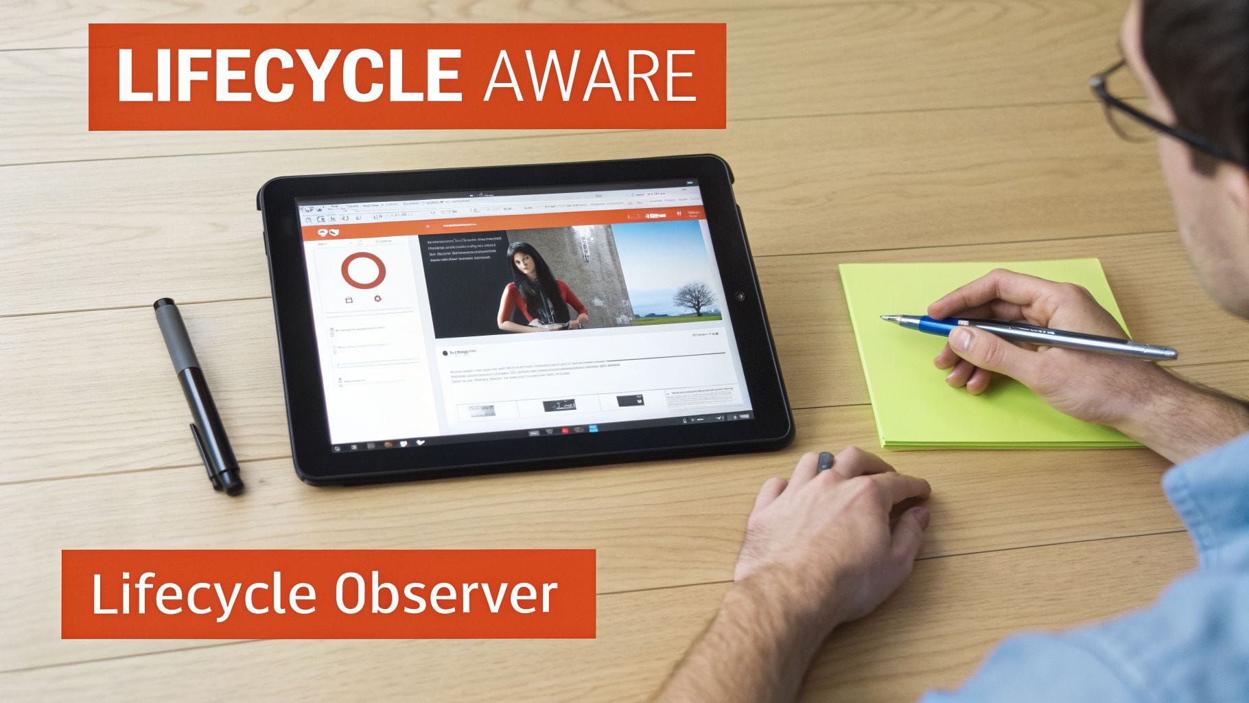 A person sits at a wooden table, using a tablet displaying a webpage. They hold a pen, with a bright green notepad nearby and a black pen next to the tablet, featuring text about lifecycle a