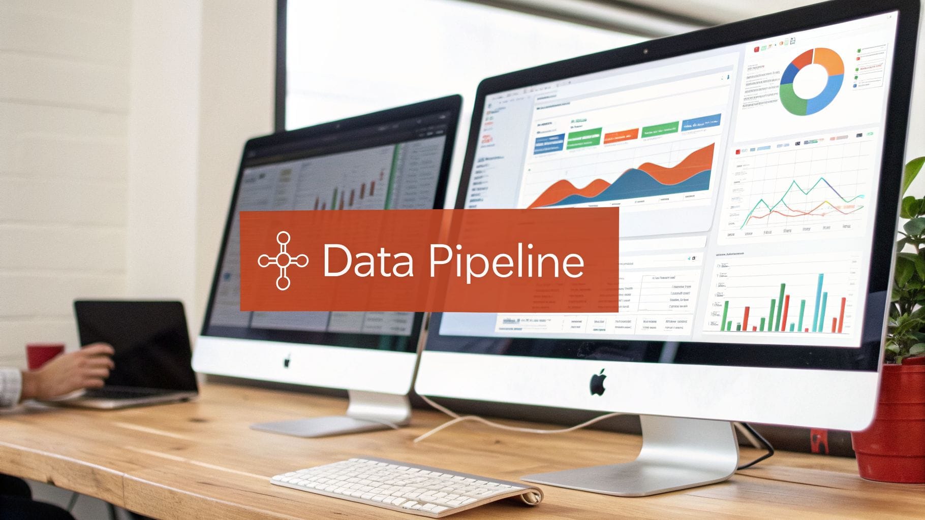 Two iMacs on a wooden desk display various data analytics graphs and charts. The text "Data Pipeline" is overlaid in bold white on a reddish-orange background. A laptop is visible to the lef