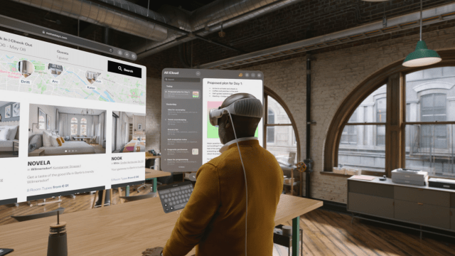 A person wearing a VR headset stands at a desk, interacting with floating app screens showing a hotel booking interface and an iCloud dashboard in a modern office setting.